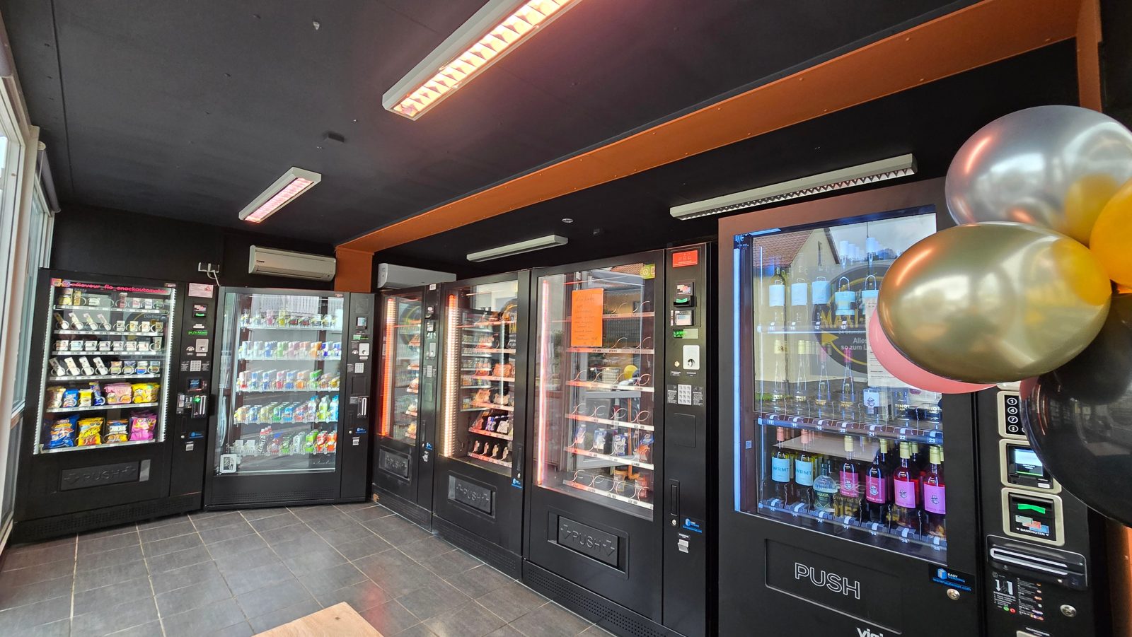 E-Kiosk von innen mit Automaten für Snacks, Getränke, Wurst vom Dorf-Metzger und Wein vom Winzer